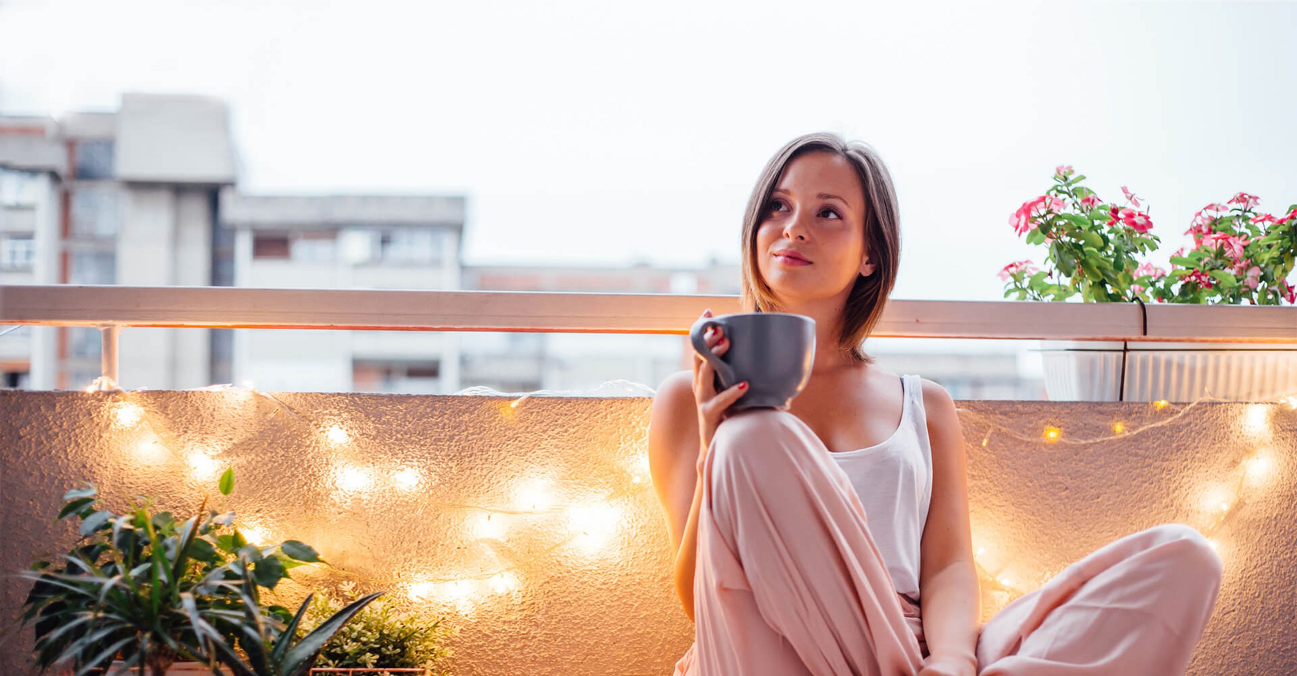Frau trinkt Tee auf ihrem Balkon